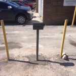 A small grey mail box between to yellow concrete polls. This is used for dropping off payments to the water department.