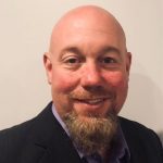 Photo of David Bates, a bald man with a short, light brown beard that does not go up the sides of his face.