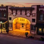A photo of the Sesser Opera House at sunset. Streetlights are on and the Opera House is light up by an arch of lights above its entryway.