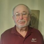 Photo of Wayne Shannon, an older man with short grey hair, a short trimmed beard, and glasses.